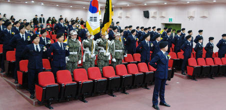 입단식 모습으로 멀리서는 많은 학생들이 일어서 있고 그 중앙에 대표로 보이는 학생이 서 있다.